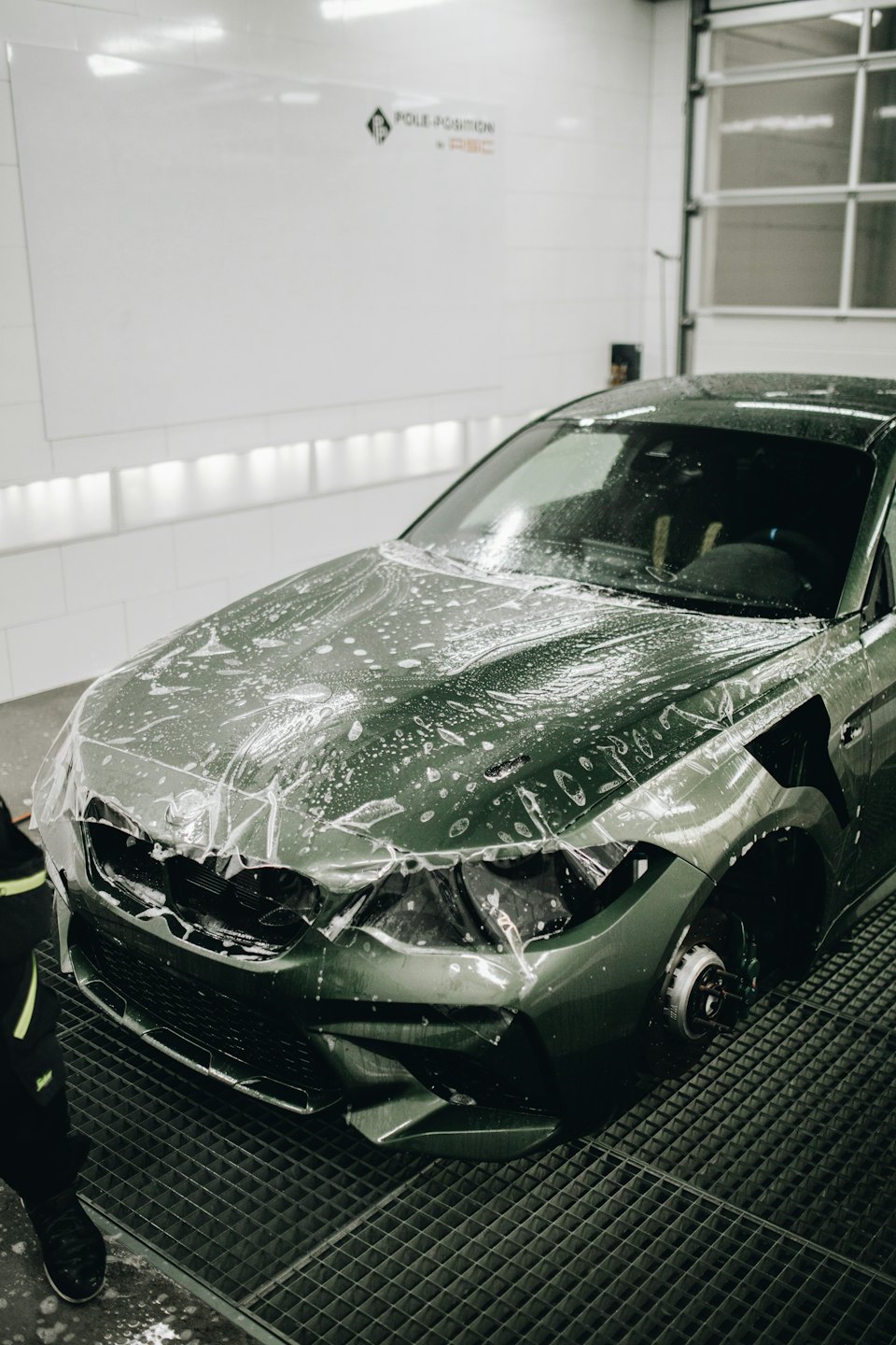 Technician applies protective film to a green sports car.